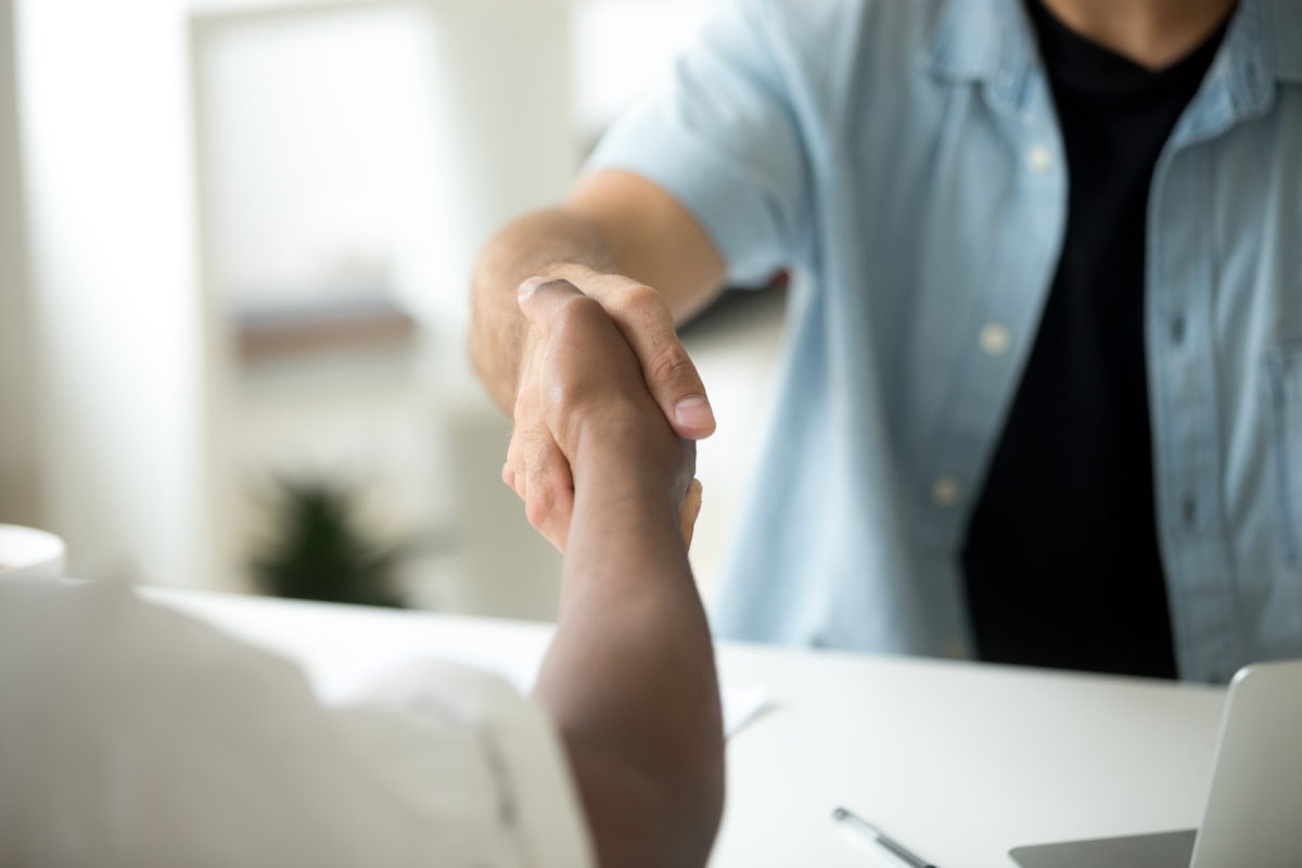 Close up of multiracial handshake over office desk